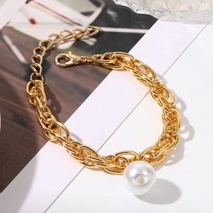 Macro view of gold chunky chain link bracelet with oversized white pearl pendant detail