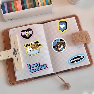 Detail of cute cat and dog stickers on a grid notebook with English quotes