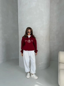 Close-up of wine red half-zip sweatshirt with Elegante Look print and grey joggers