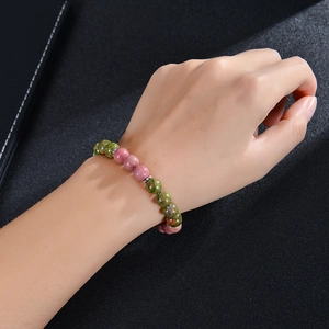 Detail of beaded fertility bracelet with green aventurine and pink beads on a wrist