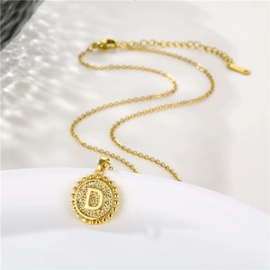Gold round pendant necklace with letter D and beaded edge on a thin link chain