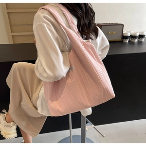 Nahaufnahme der rosa gefalteten Stofftasche mit OU SHLF-Label am Schultergurt