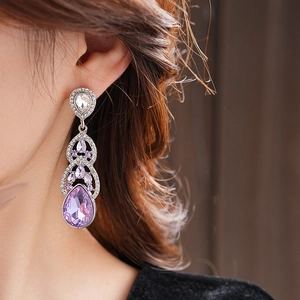 Gros plan détaillé de boucles d'oreilles pendantes en cristal violet et argent sur modèle