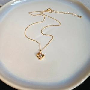 Detail of 18k gold plated necklace with a geometric pendant and sparkling zircon