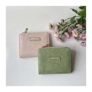 Detail view of pink and green retro short wallets with textured lychee grain leather finish