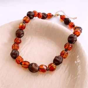 Détail macro de perles ambre et café avec fermoir doré sur une assiette en céramique