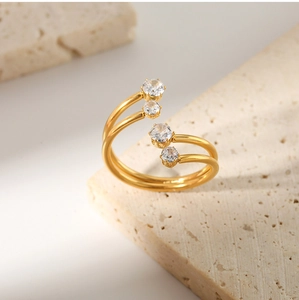 Detail of gold-plated open ring featuring staggered white zircons on a beige stone base