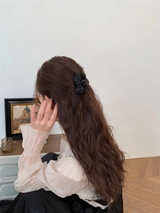 Vue de côté d'une pince à cheveux à nœud en satin noir portée dans un cadre intérieur
