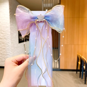 Close-up of gradient tulle bow hair clip with rhinestone star and pearl chains