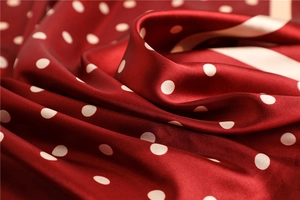 Macro shot of dark red silk-like square scarf with white polka dots showing smooth texture