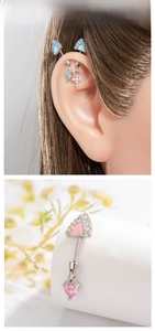 Industrial barbell earring detail with heart and cross zircon pendants in blue and pink