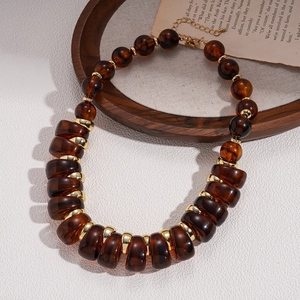 Detail of amber acrylic beads and golden metal spacers on a vintage boho necklace