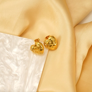 Eleganti orecchini a cuore dorati con trama intrecciata su sfondo di seta lussuosa