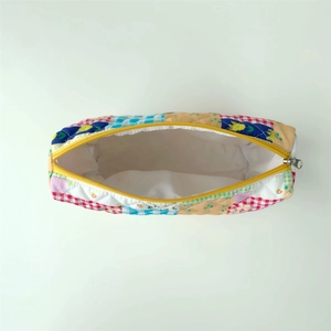 Macro view of quilted patchwork makeup bag with yellow zipper and soft white lining