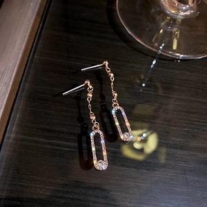 Macro view of rose gold oval drop earrings featuring pavé crystals and long chain tassels