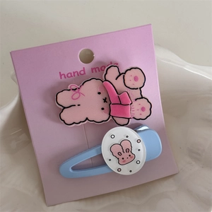 Détail d'une mignonne pince à cheveux lapin rose et barrette bleue sur carte