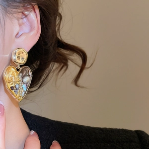 Detail of vintage heart earrings with gold hammer texture and embedded pearls