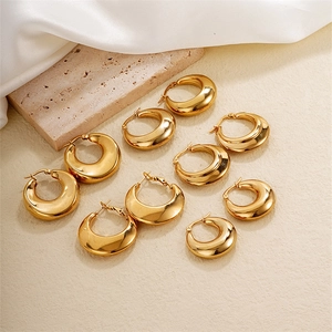 Five pairs of trendy chunky gold hoop earrings displayed on aesthetic stone and silk background