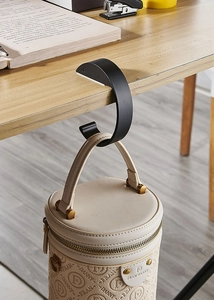 Black portable U-shaped desk hook holder for bag and headphones on a wooden table edge
