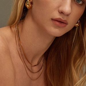 Layered gold-plated stainless steel necklaces and matching hoop earrings on a model