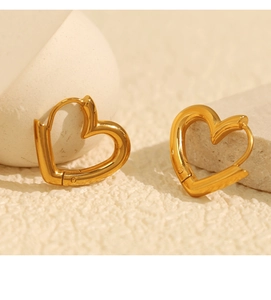 Macro shot of gold heart-shaped hoop earrings with a latch back on textured stone