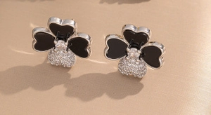 Macro view of clover studs with black onyx-style inlay and micro-pave crystals