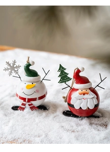 Close-up of spherical metal Santa and Snowman ornaments on a snowy background