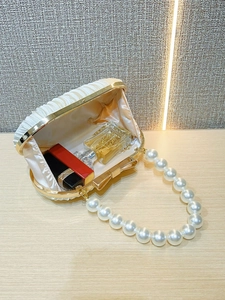 Detail der cremefarbenen Abendtasche mit Goldrahmen und elegantem Perlenhenkel-Design