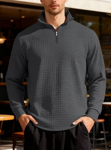 Detail of dark grey waffle textured fabric on a men's half-zip standing collar sweatshirt
