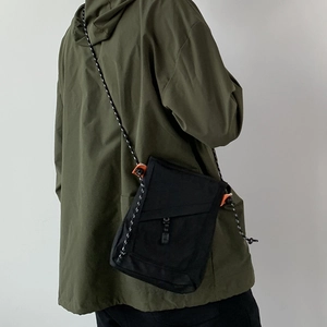 Black canvas crossbody bag styled with olive parka for urban outdoor aesthetic