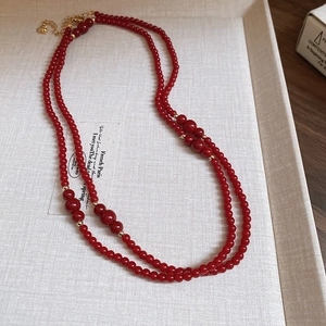 Close-up of double-layer red beaded necklace with golden spacers and lobster clasp