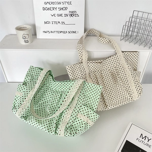 Detail of canvas tote bag with polka dots and delicate white lace trim on the handles