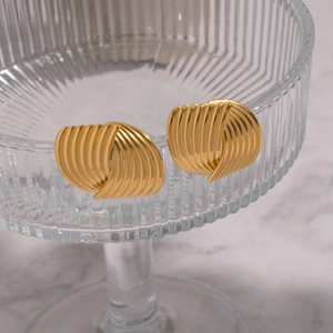 Detail von 18K vergoldeten Muschel-Ohrringen an einem schicken Glasbehälter