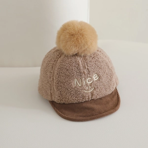 Détail de la broderie Nice smiley et du pompon doux sur un bonnet d'hiver pour bébé