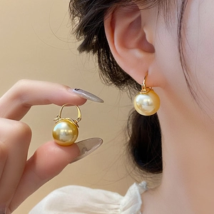 Makroansicht eleganter 18K vergoldeter Perlen-Ohrringe, präsentiert von einem Model
