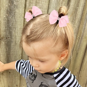 Detail shot of a young girl wearing pink polka dot bow hair clips with rhinestones