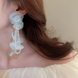 Boucles d'oreilles fleurs en tulle bleu clair avec glands en cristal sur le modèle