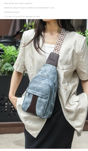 Blue denim crossbody chest bag with vintage pattern strap shown on model outdoors