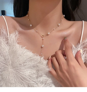 Detailed view of elegant gold Y-shaped pearl necklace on female model's collarbone