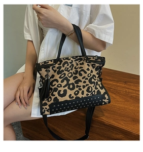 Close-up of leopard print tote bag with silver studs, black leather trim and fringe detail
