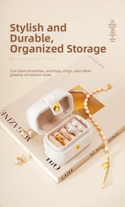Close-up of a white velvet travel jewelry box featuring gold snap button and ring slots