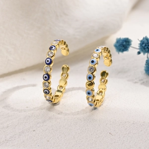 Macro detail of gold-plated Evil Eye hoop earrings with blue enamel and zircon stones