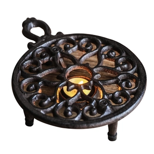 Chauffe-thé vintage en fonte avec motif à volutes creuses et lueur de bougie