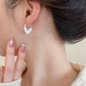 Close-up of elegant heart-shaped pearl drop earring worn by a model in warm light