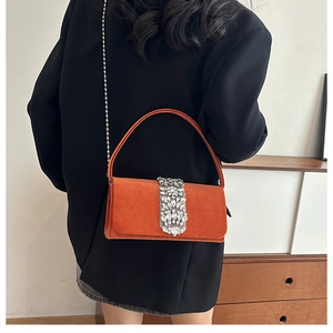 Detail of orange velvet evening bag with sparkling rhinestone buckle and gold chain strap