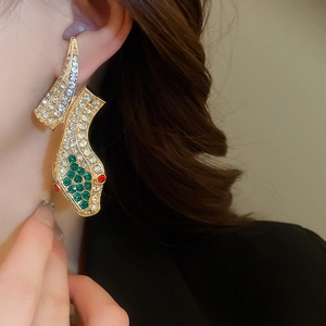 Close-up of vintage gold snake earrings with red and green rhinestones on a model