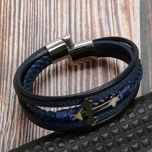 Detail of dark blue multi-layer braided leather bracelet with polished metal cross charm