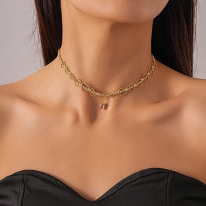 Gros plan d'un collier ras de cou doré avec zircons et pendentif en forme de poire