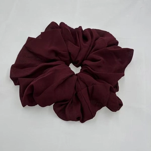 Detailed view of a dark red chiffon hair scrunchie with soft fabric texture on white background