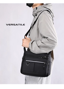 Side view of black nylon crossbody bag showing multiple pockets and adjustable strap